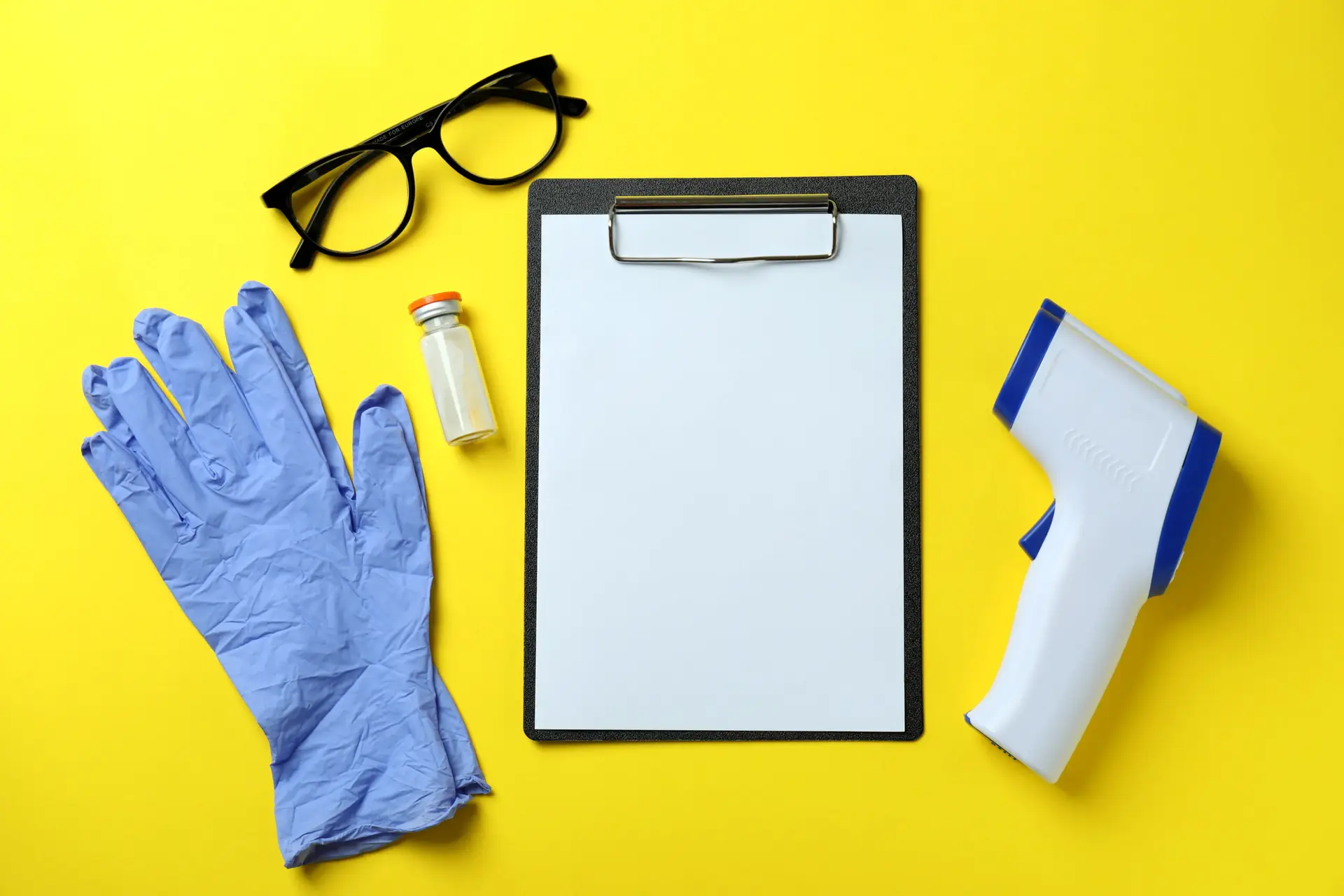 Medical tools and thermometer gun on yellow background